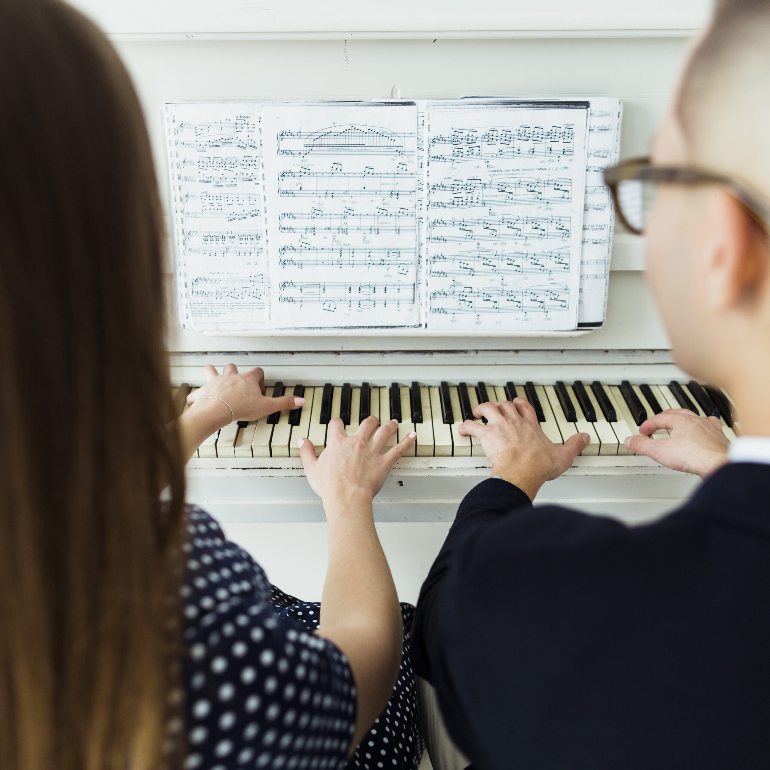 Close Up Couple Playing Piano With Musical Sheet